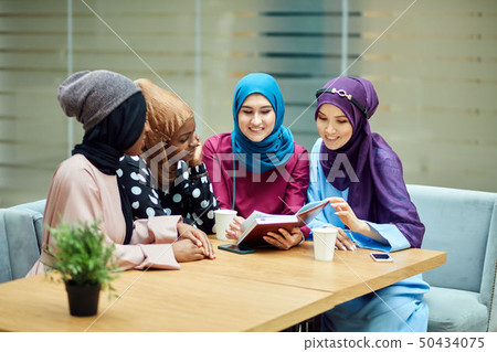 Muslim young women of diverse ethnicity talking about new book of famous author Muslim young women of diverse ethnicity talking about new book of famous author 50434075