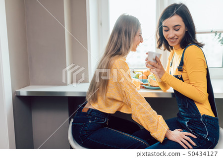two awesome girls gossipping while drinking coffee 50434127