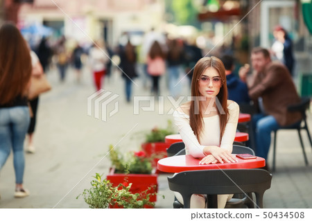 Portrait of a happy beautiful brunette sitting in a european cafe 50434508