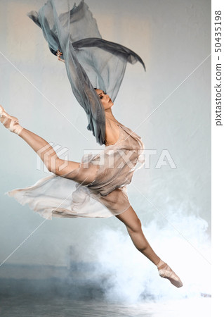 Ballerina wearing grey transparent clothes jumping on stage with smoke effect 50435198