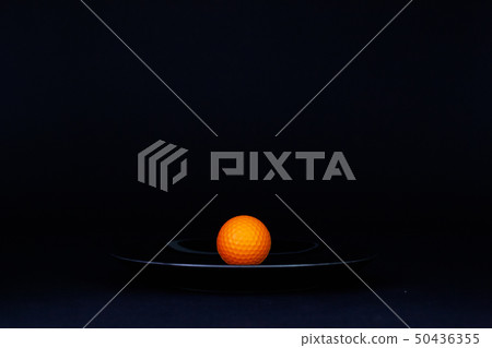 Black plate and  orange golf ball on the black 50436355