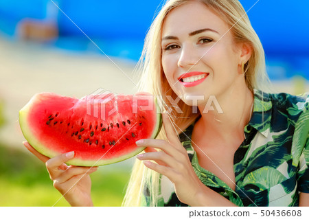 Portrait of cute girl makes funny face and smile with watermelon slices. Beautiful woman eating ripe 50436608