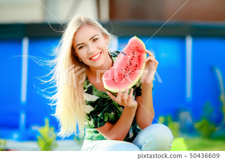 Portrait of cute girl makes funny face and smile with watermelon slices. Beautiful woman eating ripe Portrait of cute girl makes funny face and smile with watermelon slices. Beautiful woman eating ripe 50436609