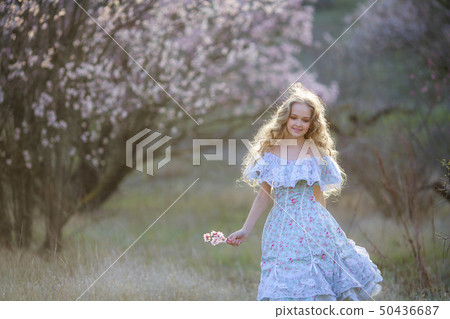 Sweet woman in a beautiful dress dancing in a park with long hair Sweet woman in a beautiful dress dancing in a park with long hair 50436687