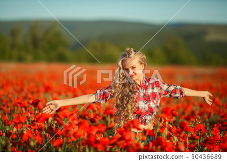 Young blonde in a red shirt in the poppy flower field. Young blonde in a red shirt in the poppy flower field. 50436689