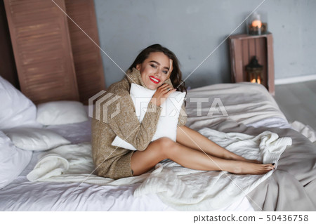 Close up portrait of an excited young woman opening present box while lying in bed at home Close up portrait of an excited young woman opening present box while lying in bed at home 50436758