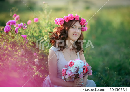 A bride in a white dress holds a bouquet of roses and callas on the background of green grass. A bride in a white dress holds a bouquet of roses and callas on the background of green grass. 50436784