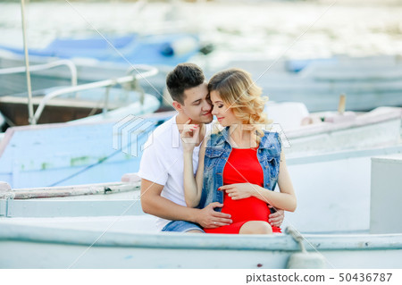 Young couple hugs and relaxing at dock near boat, on sunny summer day. Woman and man in fashionable 50436787
