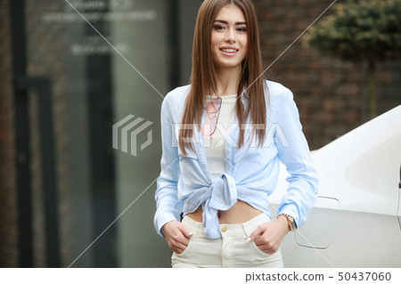 Attractive girl in fluffy jacket standing on street, catching the last lights of the autumn sun Attractive girl in fluffy jacket standing on street, catching the last lights of the autumn sun 50437060