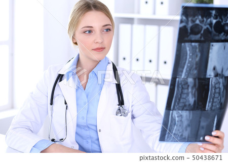 Doctor woman examining x-ray picture near window in hospital. Surgeon or orthopedist at work Doctor woman examining x-ray picture near window in hospital. Surgeon or orthopedist at work 50438671