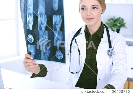 Doctor woman examining x-ray picture near window in hospital. Surgeon or orthopedist at work 50438720