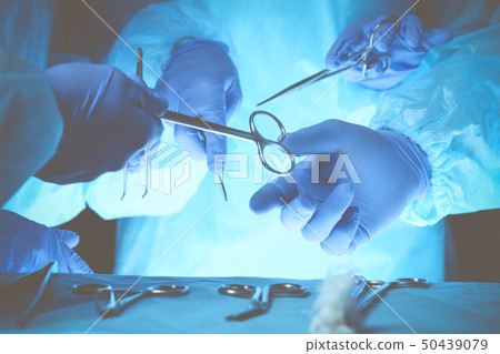 Surgeons hands holding surgical scissors and passing surgical equipment, close-up. Health care and Surgeons hands holding surgical scissors and passing surgical equipment, close-up. Health care and 50439079