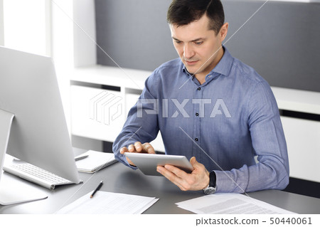 Businessman working with tablet computer in modern office. Headshot of male entrepreneur or company Businessman working with tablet computer in modern office. Headshot of male entrepreneur or company 50440061