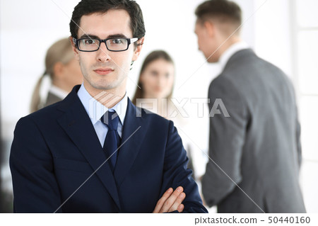Headshot of businessman standing straight with colleagues at background in office. Group of business Headshot of businessman standing straight with colleagues at background in office. Group of business 50440160