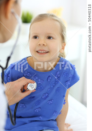 Doctor examining a little girl by stethoscope. Happy smiling child patient at usual medical 50440318