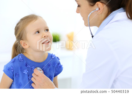 Doctor examining a little girl by stethoscope. Happy smiling child patient at usual medical 50440319