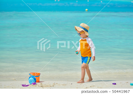 Three year old toddler playing on beach Three year old toddler playing on beach 50441967
