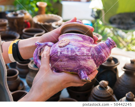 Close up of woman hands with ceramic kettle Close up of woman hands with ceramic kettle 50442245