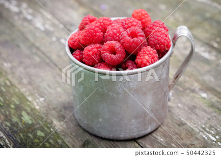 Vintage rustic mug full of raspberry berries. Vintage rustic mug full of raspberry berries. 50442325