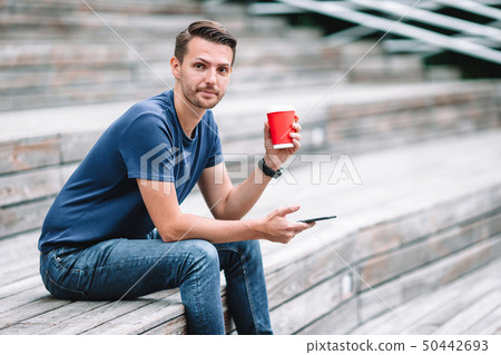 Man is reading text message on mobile phone while walking in the park Man is reading text message on mobile phone while walking in the park 50442693