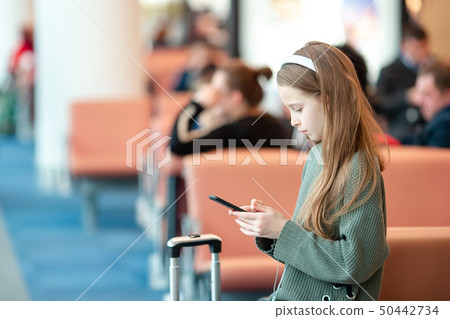 Adorable little girl at airport in big international airport near window Adorable little girl at airport in big international airport near window 50442734