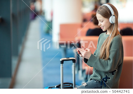 Adorable little girl at airport in big international airport near window Adorable little girl at airport in big international airport near window 50442741