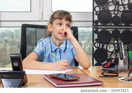 Eight-year-old girl thoughtful at the table in the 50443925
