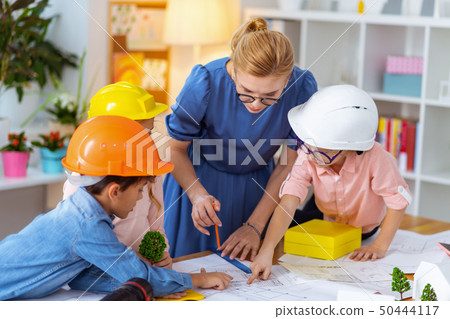 Pupils in helmets standing near teacher after drawing sketches 50444117