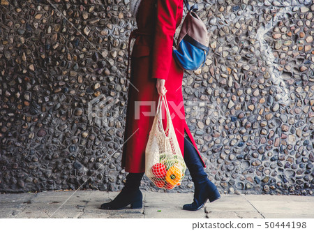 Style woman in red coat and net bag waking home after shopping. Style woman in red coat and net bag waking home after shopping. 50444198