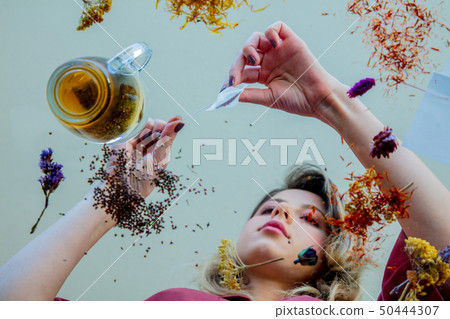 girl from under glass table while she prepares leaves before brew a tea 50444307