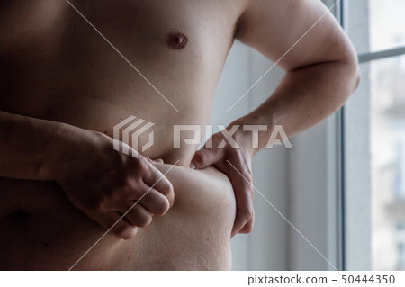 Fat guy holding his fat in hand 50444350