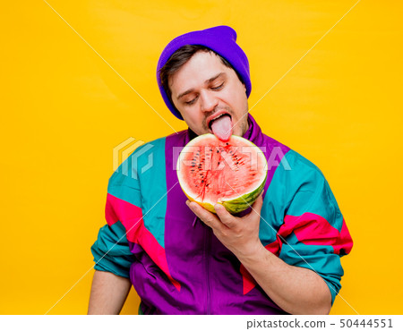 man in 90s clothes with watermelon on yellow background. 50444551