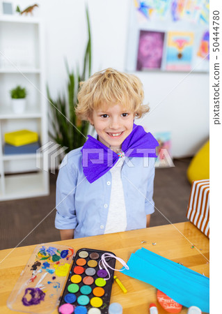 Boy smiling wearing paper bow standing near table Boy smiling wearing paper bow standing near table 50444780