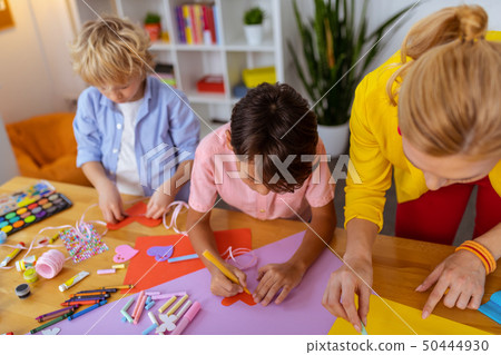 Boys standing near teacher while making cutouts and painting Boys standing near teacher while making cutouts and painting 50444930