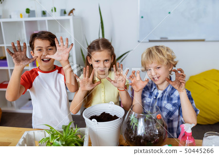 Pupils showing dirty hands after potting plants at ecology lesson 50445266