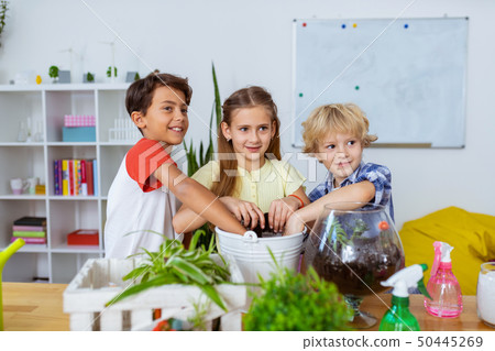 Excited schoolchildren potting cactuses and plants together 50445269
