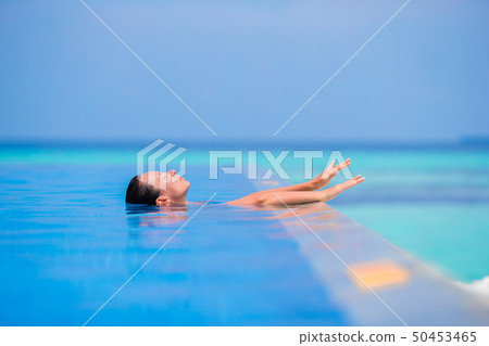 Young woman enjoying water and rest in outdoor swimming pool 50453465