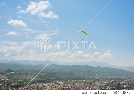 paragliding under blue sky in the town 50453872