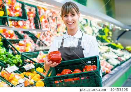 Clerk in a supermarket showing fresh vegetables Clerk in a supermarket showing fresh vegetables 50455398