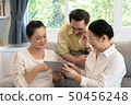 senior asian firend sitting on sofa using digital 50456248