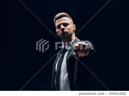Serious handsome man in black suit pointing his 50461068