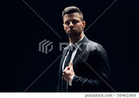 Handsome confident man in black suit on dark Handsome confident man in black suit on dark 50461069