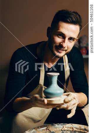Smiling handsome man showing handmade ceramic pot Smiling handsome man showing handmade ceramic pot 50461108