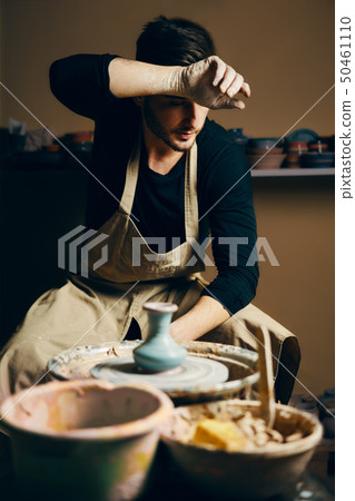 Tired potter modeling ceramic pot on a potter's 50461110