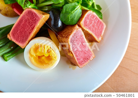 Nicoise salad with grilled tuna and boiled egg on a wooden background, close-up Nicoise salad with grilled tuna and boiled egg on a wooden background, close-up 50461801