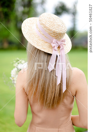Back view of young female person in body color overalls and hat. 50461827