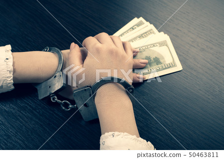 hands in handcuffs holding paper money 50463811