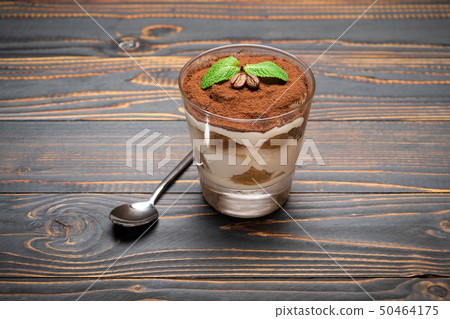 portion of Classic tiramisu dessert in a glass on wooden background 50464175