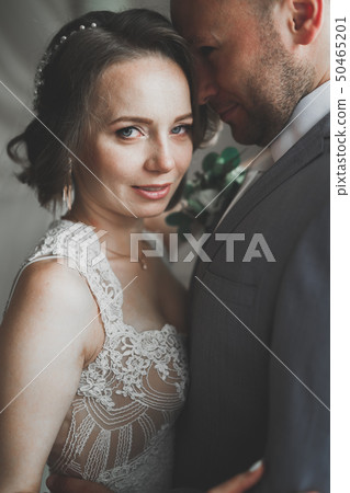 Beautiful bride and groom embracing and kissing on their wedding day Beautiful bride and groom embracing and kissing on their wedding day 50465201