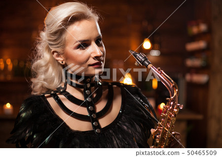 Portrait of caucasian woman singing on her saxophone in a vintage pub 50465509